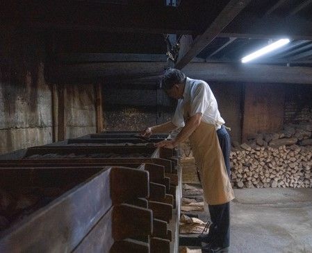 燻し行程中の鰹をチェックする店の主人