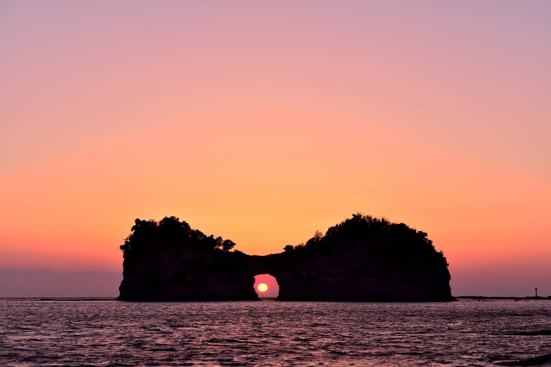 海に浮かぶ円月島。穴に夕日が収まる瞬間を見るには春と秋の彼岸の頃が狙い目。